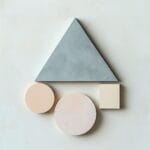 A minimalist arrangement of a triangle, circle, and square in muted colors, perfectly balanced on a plain background.